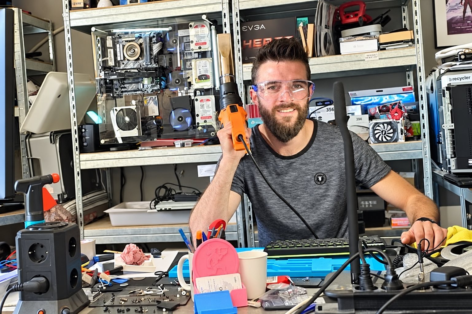 Technicien souriant dans son atelier de réparation informatique, une perceuse à la main